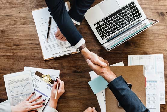 handshake over laptop and paperwork