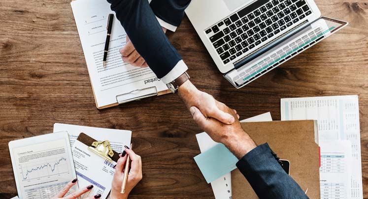 handshake over laptop and paperwork